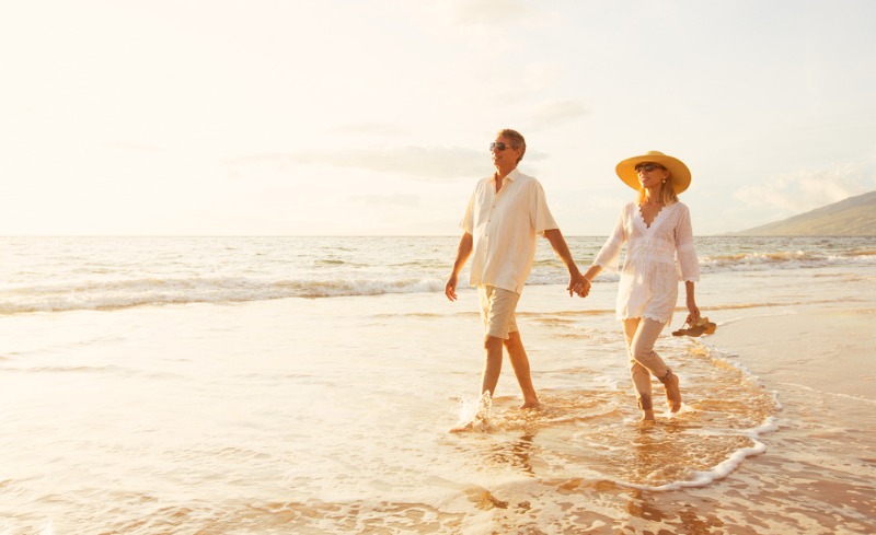 Romantic Getaways in Hawaii: A romantic couple in their early fifties walks along a beautiful shoreline in Hawai'i.